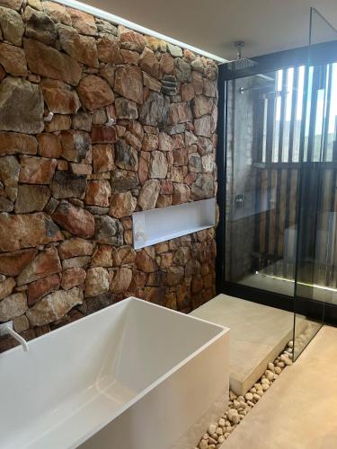 a bathroom with a stone wall and a bath tub at Old Mac Daddy in Botrivier