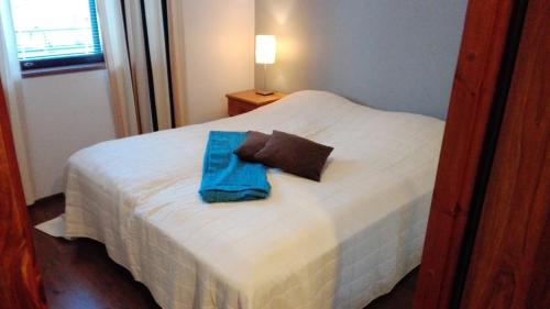 Una cama blanca con una toalla azul. en Apartment Villa Ylläs 201, en Ylläsjärvi