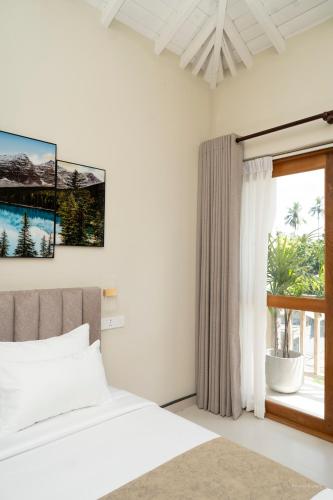 a white bedroom with a bed and a window at Orchid Resort By Paradise in Habaraduwa Central