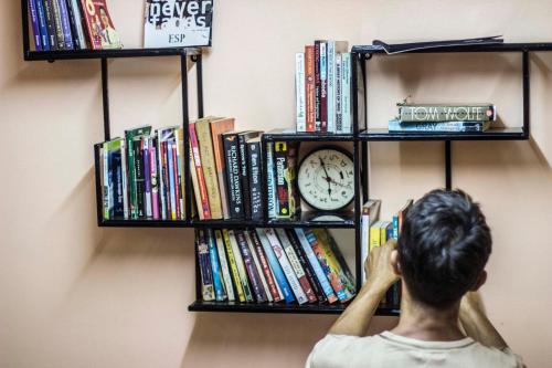 a person is looking at a clock on a book shelf at Karma Home Hostel in Phitsanulok