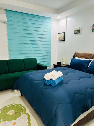 a bedroom with a blue bed and a couch at Poolside Condo in Subic Bay in Olongapo