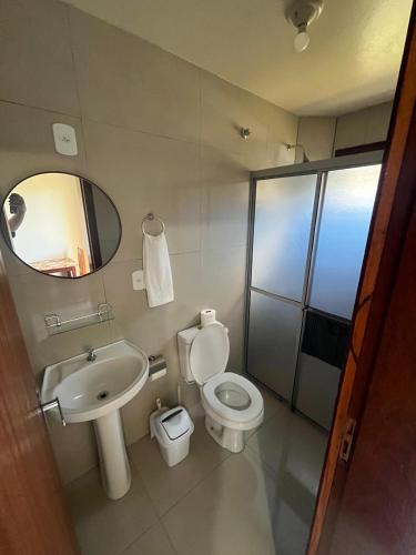 a bathroom with a toilet and a sink and a mirror at Pousada garopaba in Garopaba
