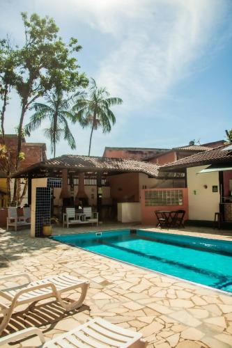 a swimming pool with chairs in front of a house at Pérola da Mata in Boicucanga