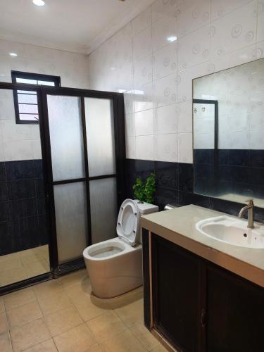 a bathroom with a toilet and a sink and a mirror at Pasadena Home in Tawau