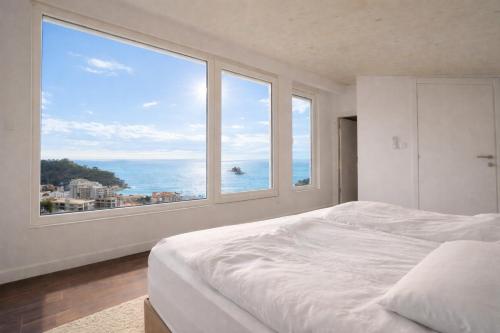 a white bedroom with a large window overlooking the ocean at Villa Blue Vista Meerblick mit Jacuzzi in Petrovac na Moru