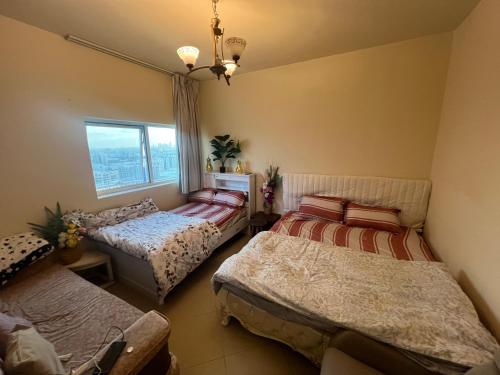 a bedroom with three beds and a window at Sahara View Guest House Prime Location on the Dubai Sharjah Border in Sharjah