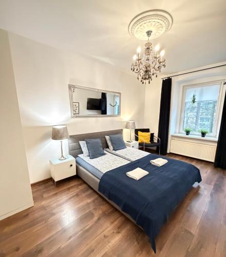 a bedroom with a large blue bed and a chandelier at Apartament Zdrój Lądek in Lądek-Zdrój