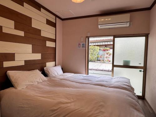 a bedroom with a large white bed with a window at Waraku No2,Guesthouse near KIX in Izumi-Sano