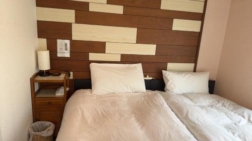 a bedroom with a bed with a wooden headboard at Waraku No2,Guesthouse near KIX in Izumi-Sano