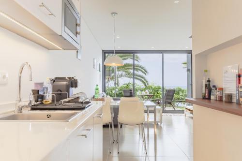 a kitchen with a sink and a table with chairs at Quinta Golfinho in Arco da Calheta