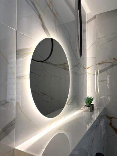 a bathroom with a round mirror on a wall at Apartament Olesno Lux in Olesno