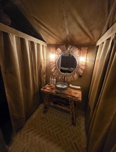 a room with a table and a mirror in a tent at Desert Paradise Lodging in Merzouga