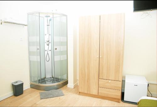 a glass shower in a room next to a wooden cabinet at Amor Lisboa Hostel in Lisbon