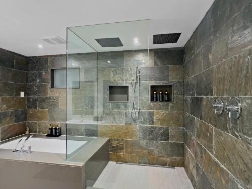 a bathroom with a shower with a tub and a sink at Hot Tub with Backyard Play Area in Toronto