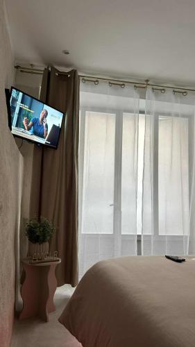 einen TV in einem Schlafzimmer mit einem Bett und einem Fenster in der Unterkunft L'intrAMOURos in Avignon