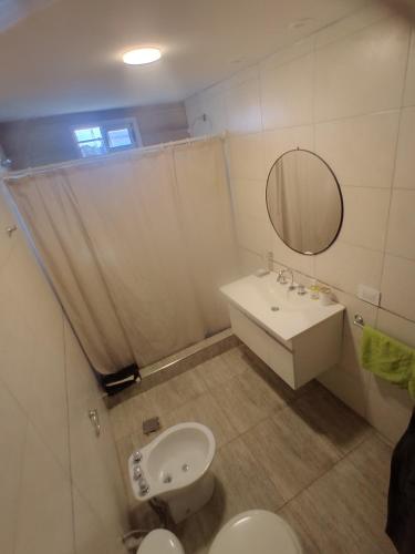 a bathroom with a sink and a toilet and a mirror at Quincho Monoambiente Con Parrilla in Balcarce