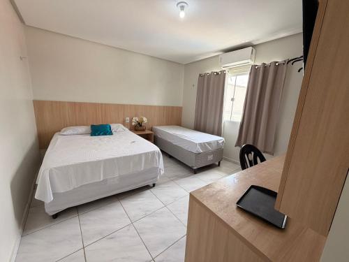 ein Hotelzimmer mit zwei Betten und einem Schreibtisch in der Unterkunft A M Hotel in São Luís