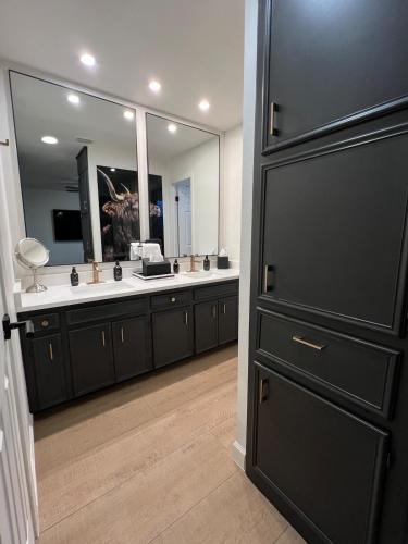 a bathroom with a large mirror and a black door at Midland Luxe, Pool, Fire Pit, Workspace, Pool Table in Midland