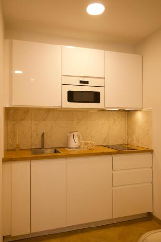 a kitchen with white cabinets and a microwave at Cozy city centre apartment in Telšiai