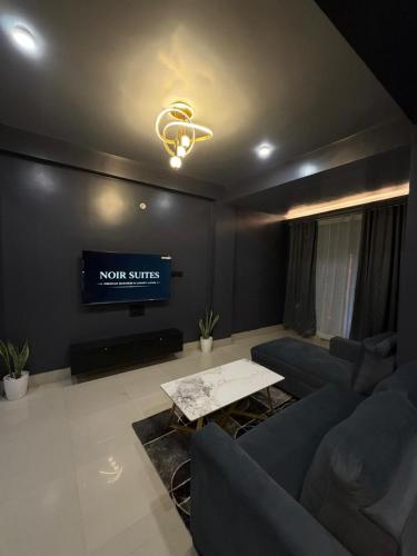 a living room with a couch and a tv at Noir Suites in Patna