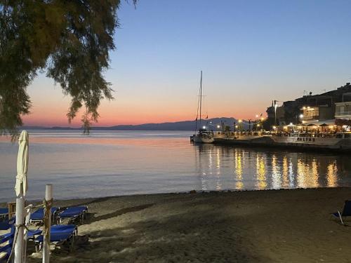 a beach with chairs and boats in the water at SUNNY STUDIO in Skala Marion