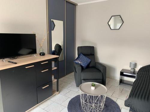 a living room with a tv and a chair and a table at studio meublé, résidence calme in Saint-Amand-les-Eaux