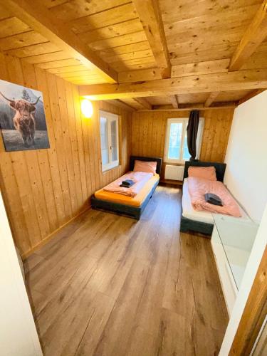 two beds in a room with wooden walls and wood floors at Appartment Happy Life - Wimmis - near Spiez-Thun- Interlaken in Wimmis