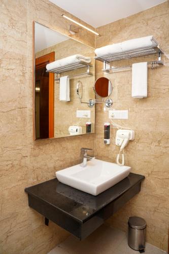 a bathroom with a sink and a mirror at Hotel Sarovaras Legacy in Bangalore