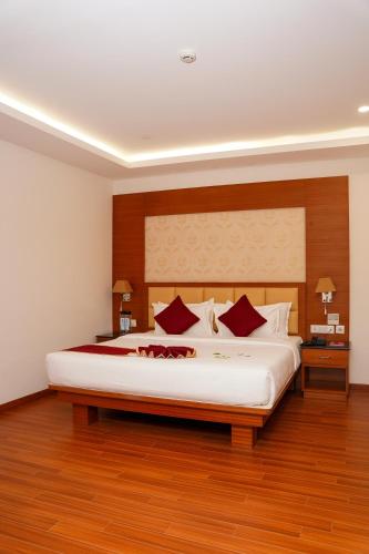 a bedroom with a large white bed with red pillows at Hotel Sarovaras Legacy in Bangalore