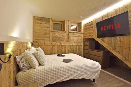 a bedroom with a bed with a netflix sign on the wall at ArtiStone - "Ancient Lodge" in Saint-Christophe
