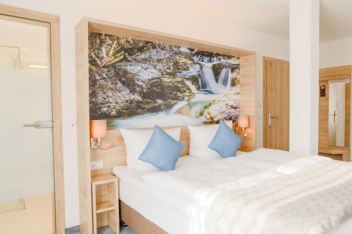 a bedroom with a large white bed with blue pillows at R&R Residenzen HOTEL in Mitterbach