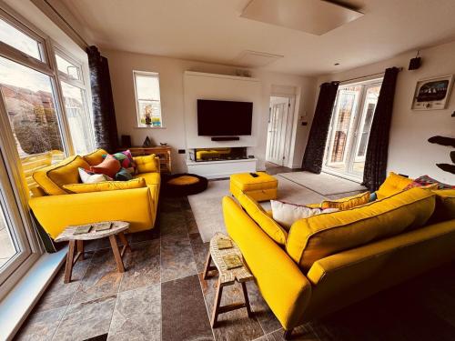 a living room with two yellow couches and a tv at 2-Bed Coastal Haven with Private Hot Tub in Lowestoft
