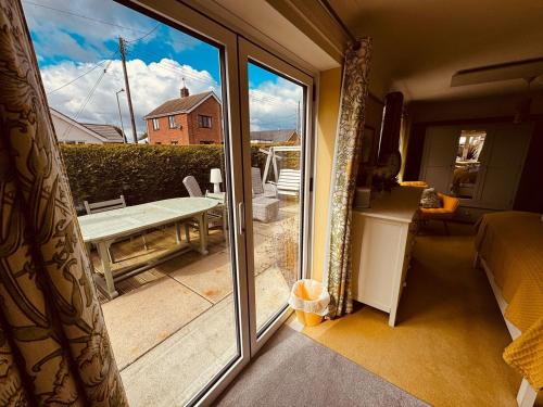 a sliding glass door leading to a patio with a table at 2-Bed Coastal Haven with Private Hot Tub in Lowestoft