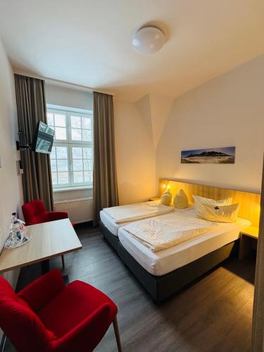 a hotel room with a bed and a red chair at Ferienhotel Alter Bahnhof garni in Prerow