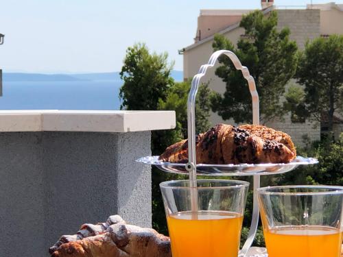 two glasses of orange juice and bread on a table at Apartments Villa Anna Sonia in Podstrana