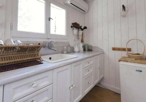 a white kitchen with a sink and a window at Odyssey Eco Farm Glamping in Galatas