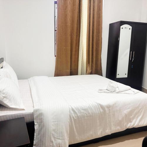 a bedroom with a white bed and a mirror at Hotel Kiara In Shillong in Shillong