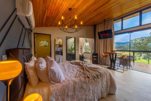 a bedroom with a bed with a large window at Recanto do Bici in Urubici