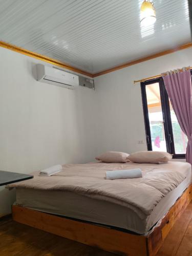 a bedroom with a bed in a room with a window at Jambu Tree Homestay in Tanjungjati