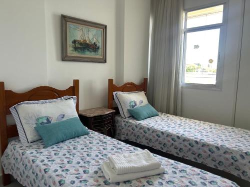 a bedroom with two beds and a window at Apartamento vista do mar, pé na areia e águas tranquilas, no cento de Guarapari in Guarapari
