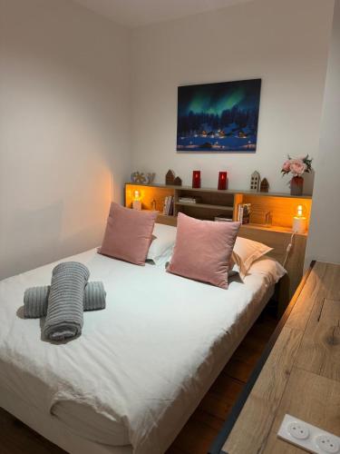 a bedroom with a large white bed with pink pillows at Cocon Des Bois - Gex Genève Mijoux in Mijoux