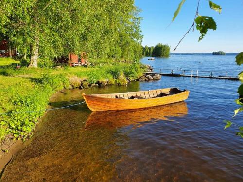 a wooden boat sitting on the water near a shore at Getaway in the wilderness in Hämeenlinna