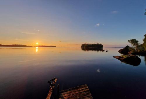 a boat on a lake with the sunset in the background at Getaway in the wilderness in Hämeenlinna