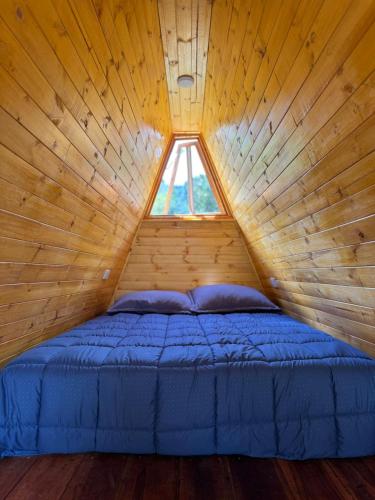 a bed in a wooden room with a window at Finca Milele in Macanal