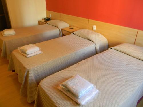 three beds in a hotel room with towels on them at Hotel Viña Del Mar in Rio de Janeiro