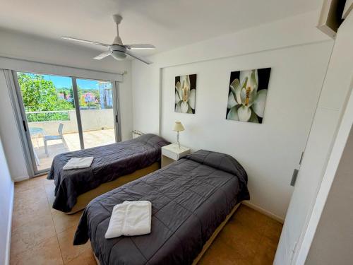 a bedroom with two beds and a ceiling fan at Duna 6 in Mar de las Pampas