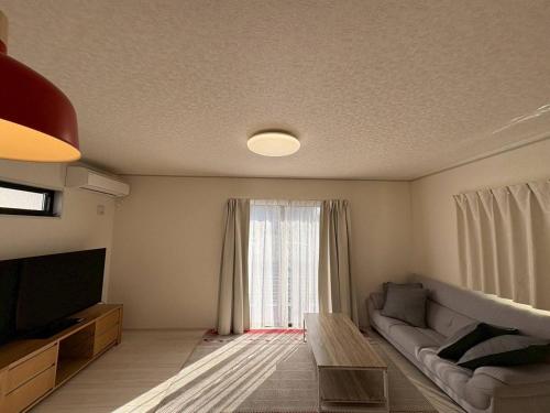 a living room with a couch and a large window at 青梅森の宿3号館新築4房車站4分 in Ome