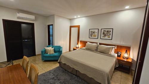 a bedroom with a bed and a table and a chair at Hotel das Palmeiras in Paracatu
