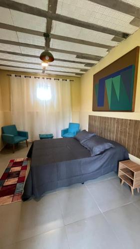 a bedroom with a large bed and blue chairs at Complexo Luquinha in Delfinópolis
