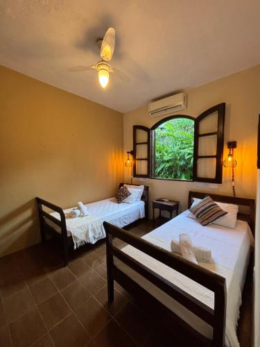 a room with two beds and a window at Pousada Recanto da Ladeira in Paraty